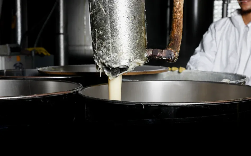 adhesive coming out of a pipe into a drum