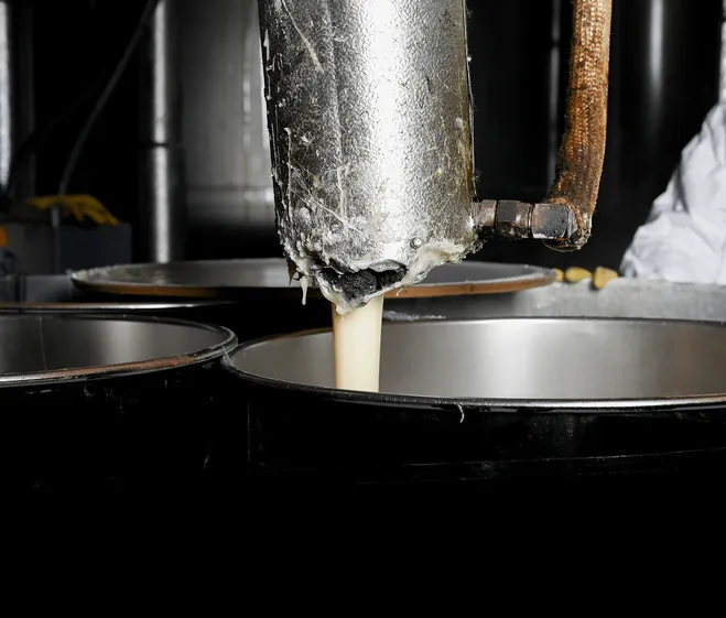 adhesive pouring out of a metal tube into a metal barrel