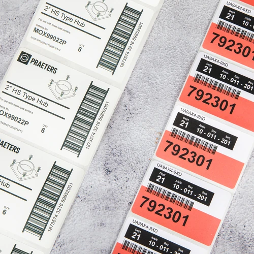 Thermal printing labels with barcodes and product information displayed on textured surface, featuring inventory tracking labels numbered 792301