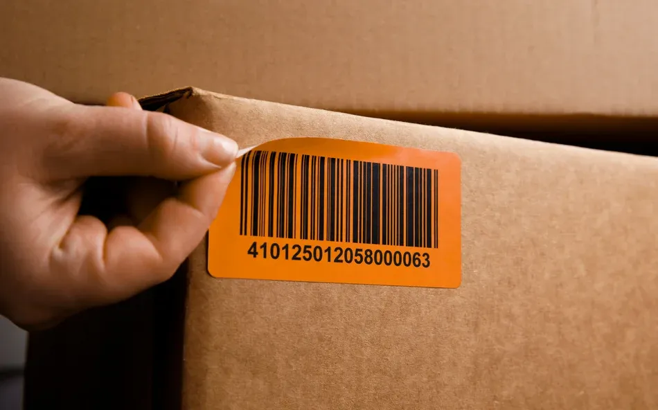 Hand peeling barcode label from cardboard box
