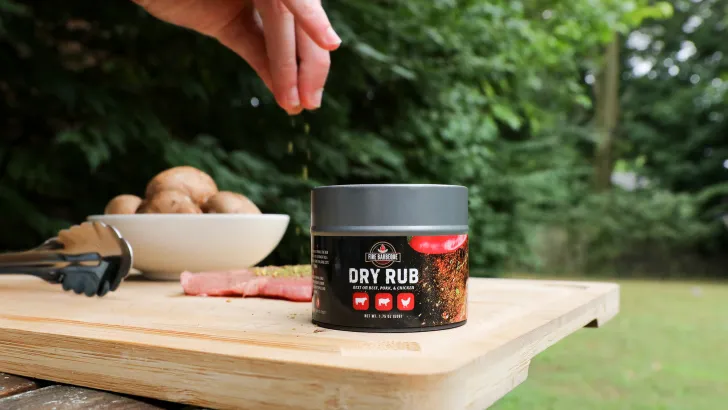 Outdoor scene with dry rub seasoning jar with bold label on wooden cutting board