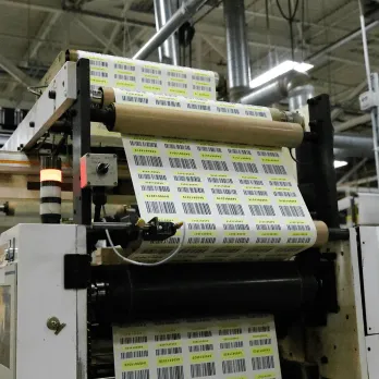 Industrial label printer producing rolls of custom thermal labels in production facility
