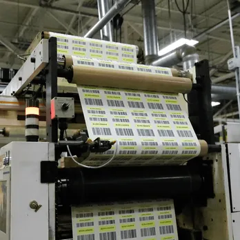 Industrial label printer producing rolls of custom thermal labels in production facility