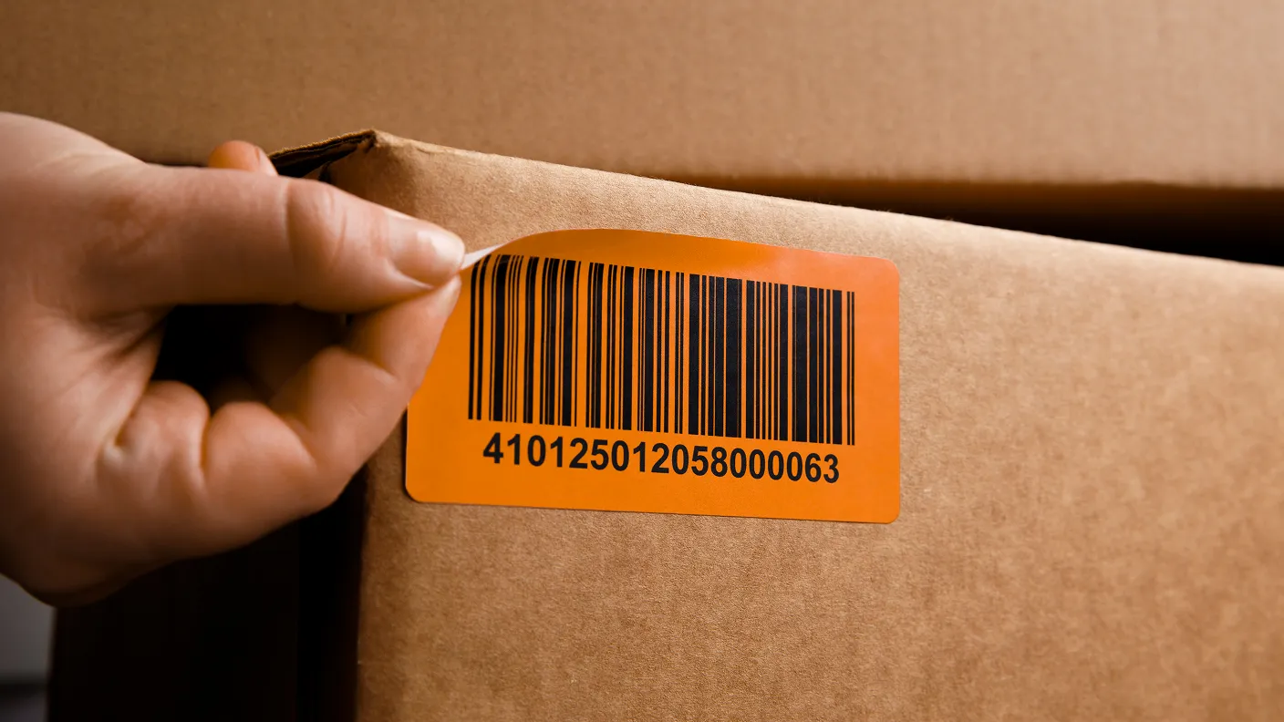a hand peeling an LPN label off of a cardboard box