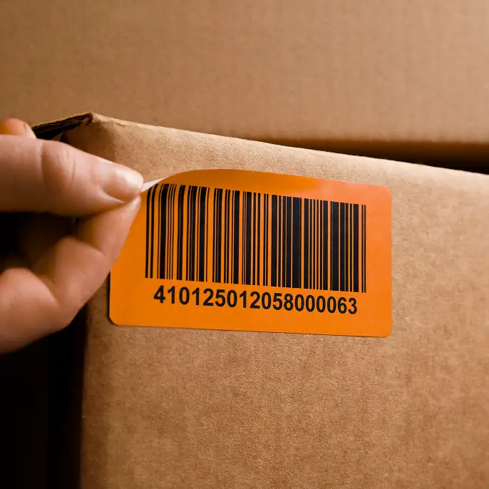 Orange LPN barcode label on cardboard box with hand holding it