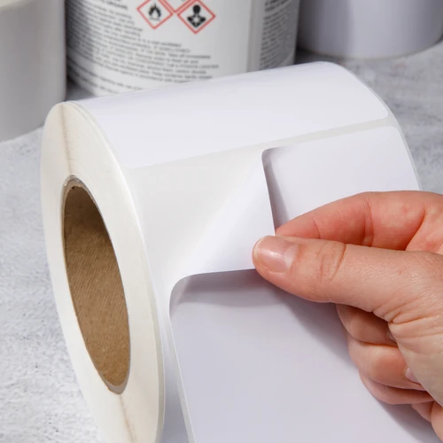 hand peeling white industrial label from roll on concrete surface