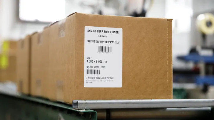 Cardboard box with thermal shipping label on warehouse conveyor belt