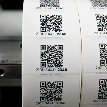 Roll of white thermal labels with QR codes wrapped around stainless container