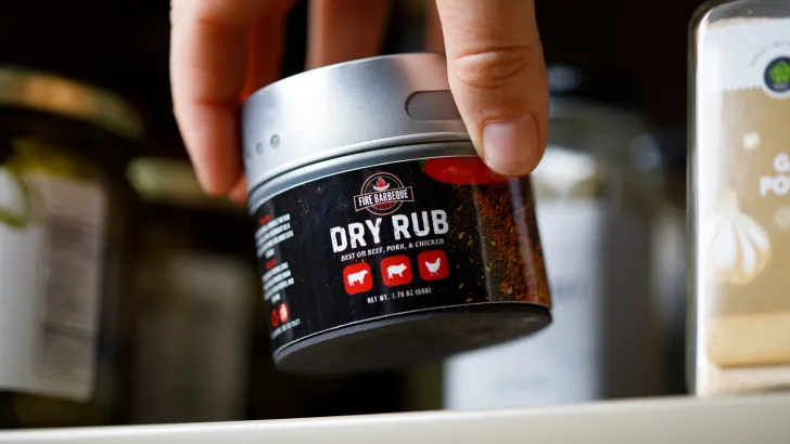 Hand holding dry rub seasoning jar with bold product label
