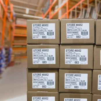 stack of cardboard boxes with barcode labels inside of a warehouse