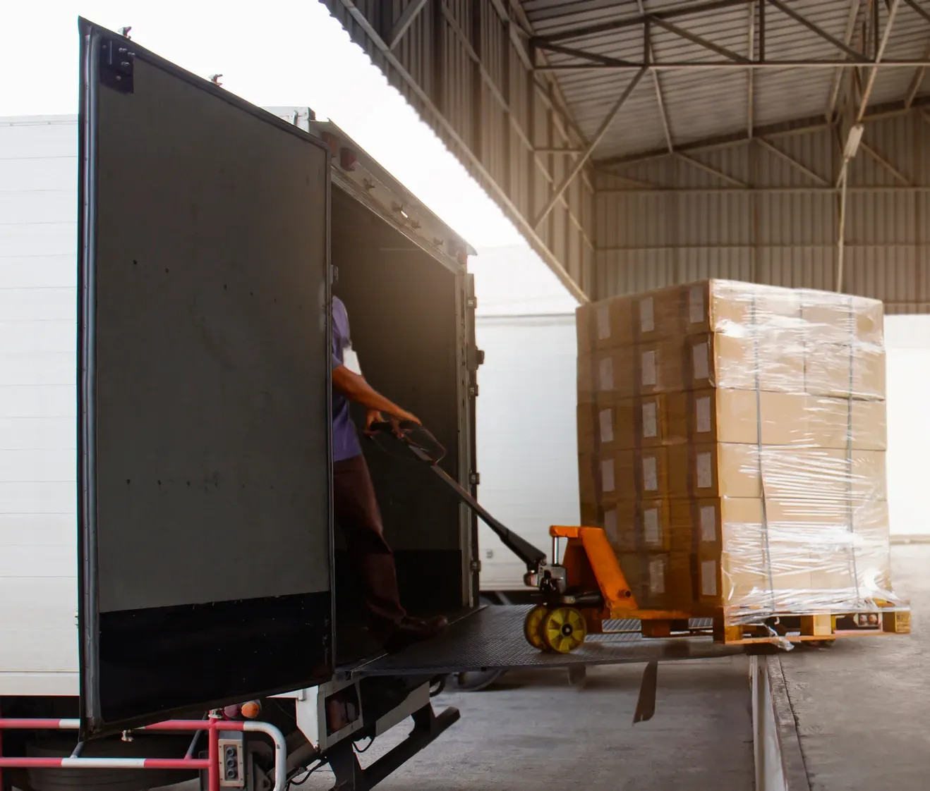 A forklift transferring a pallet of boxes from a truck
