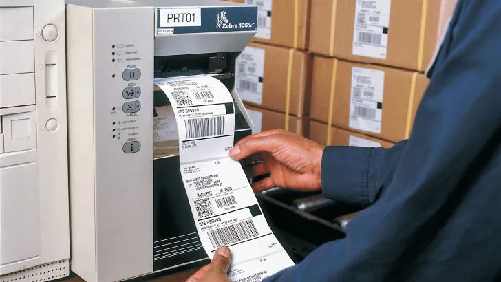 Person printing thermal shipping labels from desktop label printer