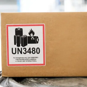 Cardboard shipping box with UN3480 lithium battery hazmat label showing handling symbols