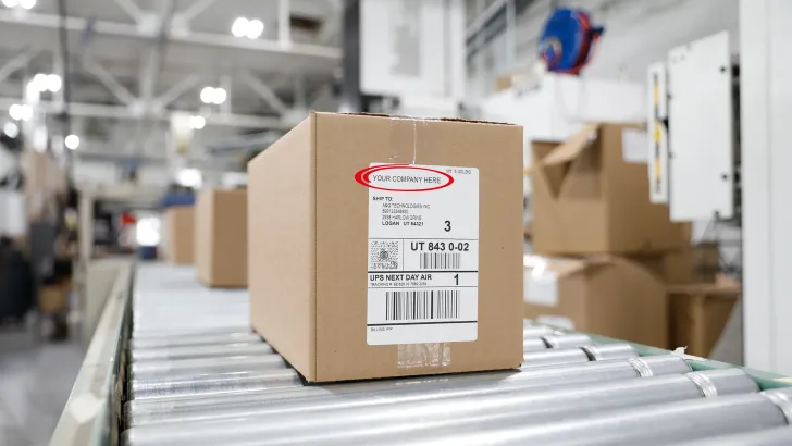 Cardboard box with thermal shipping label on warehouse conveyor belt